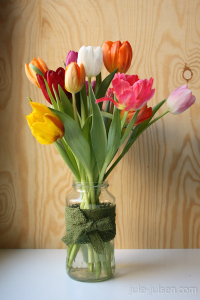 Tulpen in mit Spitzenband verziertem Haushaltsglas