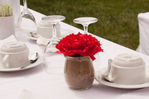 gedeckter Kaffeetisch mit roten Papierblumen in Weckgläsern 