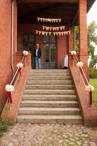 Dekoration im Eingangsbereich: Papierblüten an den Treppengeländern und Wimpelkette über dem Eingang 