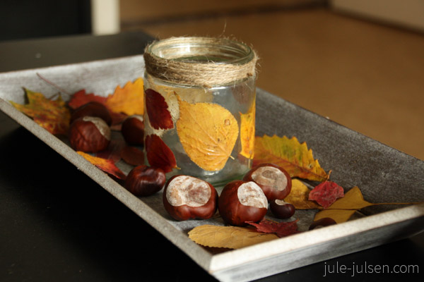 altes Marmeladenglas beklebt mit Herbstblättern