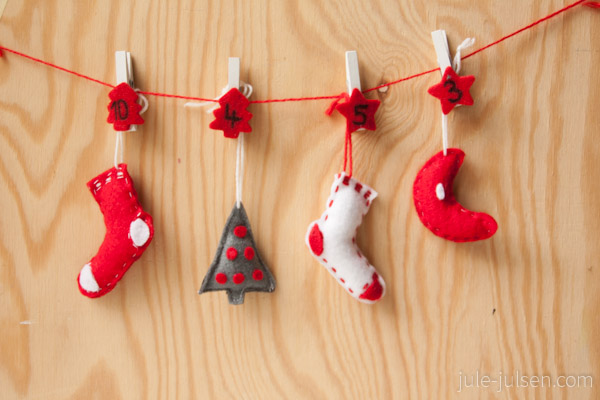 rote, weisse und graue Filzanhaenger in Form von Socken, Weihnachtsbaeumen und Monden