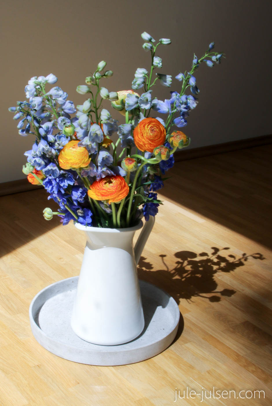 sommerlicher Blumenstrauss mit orange-gelben Ranunkeln und blau-lila farbenem Rittersporn