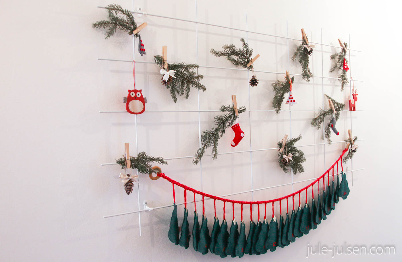 weihnachtsliche Deko mit Tannenzweigen, Flizanhängern und Kienäpfeln an einem Pflanzgitter 